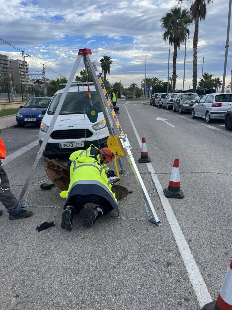 Técnicos inspeccionando una red de saneamiento en Mataró utilizando un trípode de seguridad y equipo de medición.