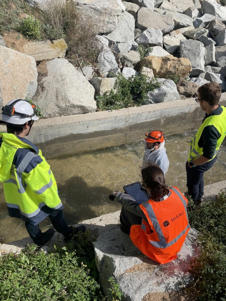 Técnicos inspeccionando una red de saneamiento en Mataró utilizando un trípode de seguridad y equipo de medición.